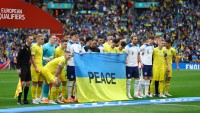 Гравці Англії та України перед матчем сфотографувалися із прапором за підписом «Мир»
